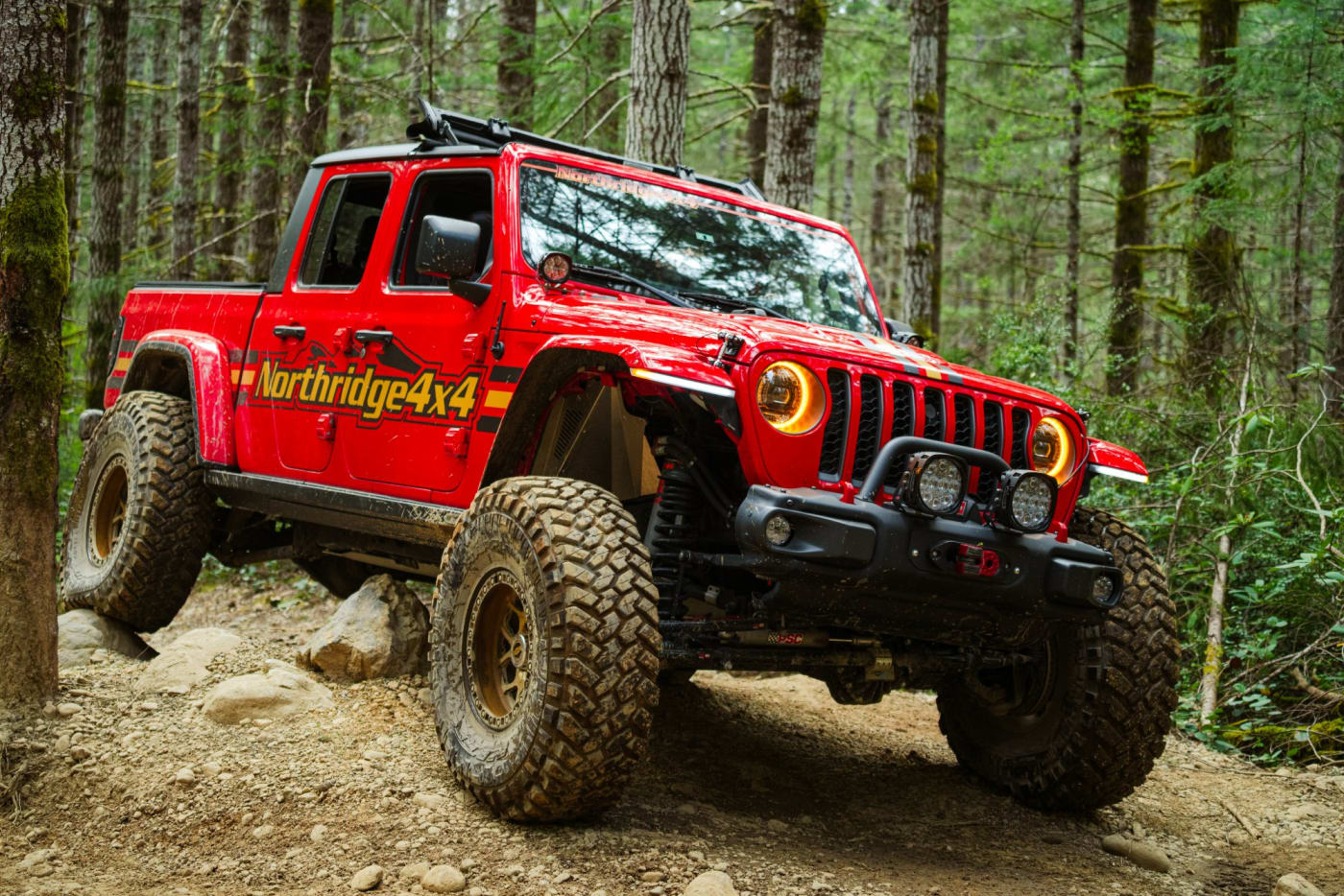 Northridge4x4 red Jeep Gladiator crawling over rocks on a forest trail